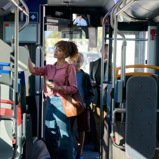 Kobieta i dziecko stoją we wnętrzu autobusu.