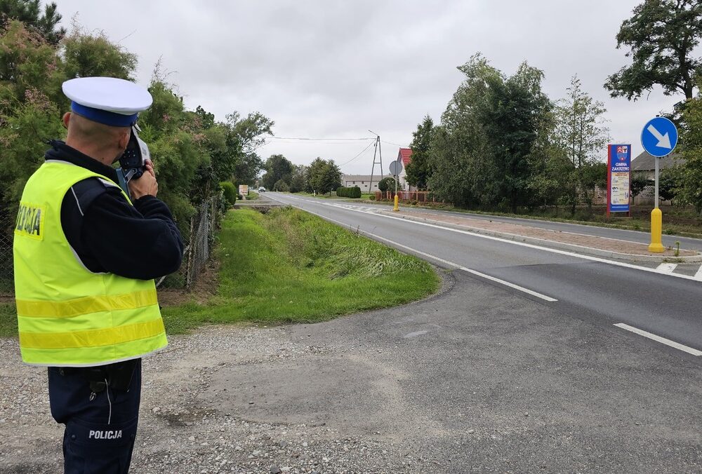 Policjant mierzący prędkość pojazdów przy drodze