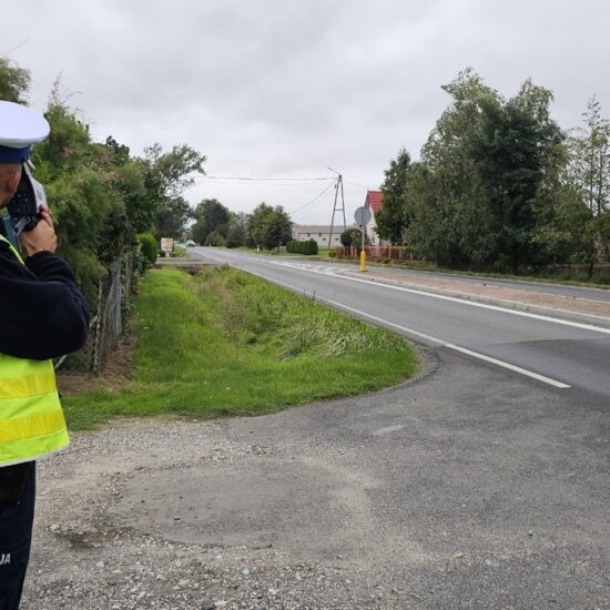 Policjant mierzący prędkość pojazdów przy drodze