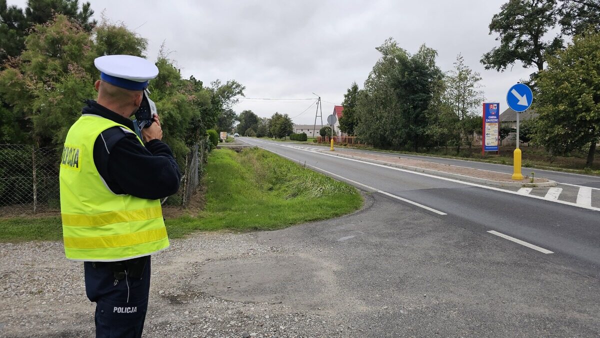 Policjant mierzący prędkość pojazdów przy drodze