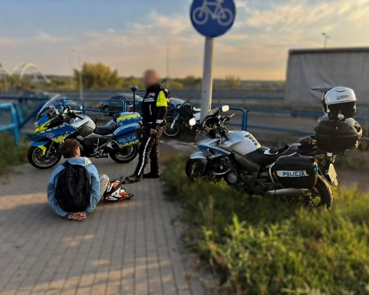 Zatrzymany mężczyzna siedzi na drodze dla rowerów obok policjanta i policyjnych motocykli w Toruniu.