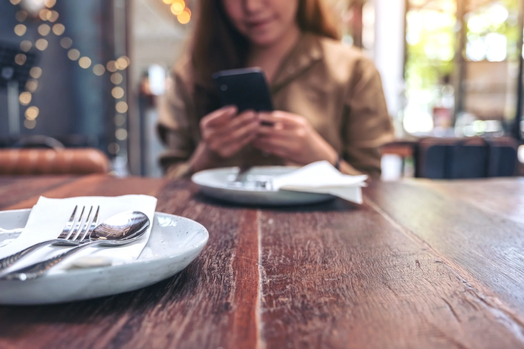 Kobieta korzystająca ze smartfona przy stoliku w restauracji