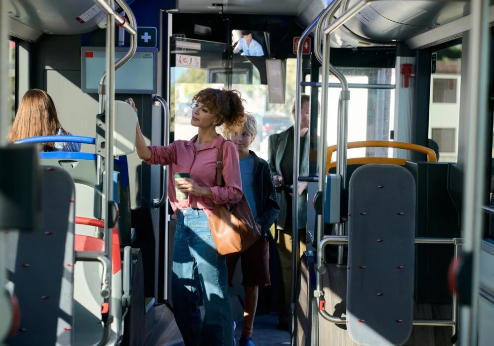 Kobieta i dziecko stoją we wnętrzu autobusu.