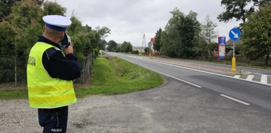 Policjant mierzący prędkość pojazdów przy drodze