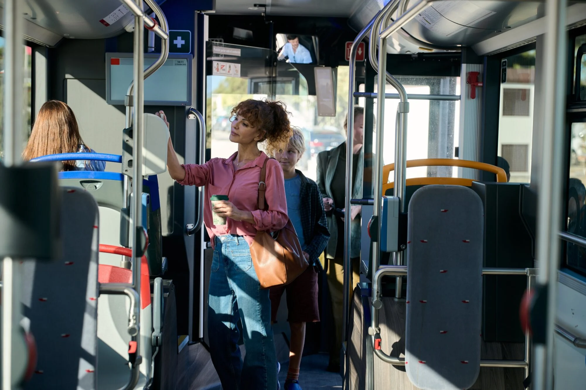 Kobieta i dziecko stoją we wnętrzu autobusu.