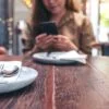 Kobieta korzystająca ze smartfona przy stoliku w restauracji