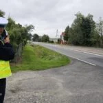 Policjant mierzący prędkość pojazdów przy drodze